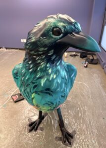 Painted crow sculpture. Greens and blues